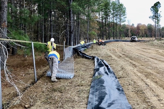 Installation crew installing silt fence and chain link