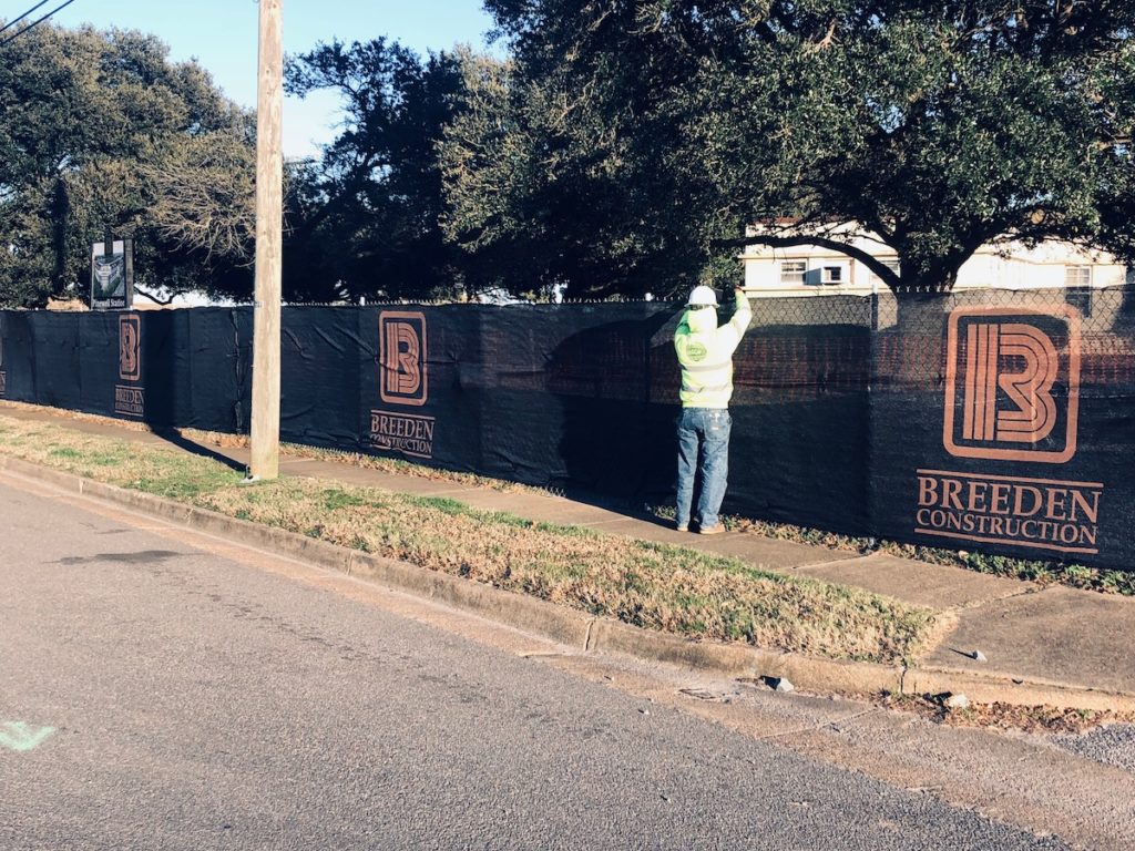 Installing black fence screen on temporary chain link fence